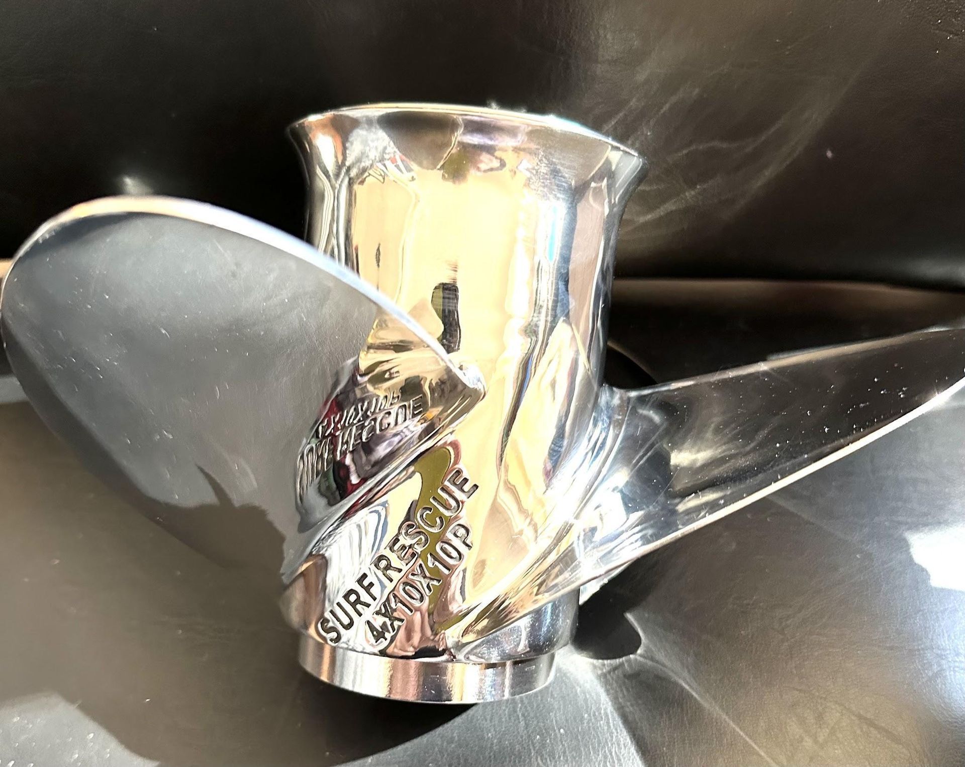 Close-up of a polished silver propeller hub with two blades against a dark background