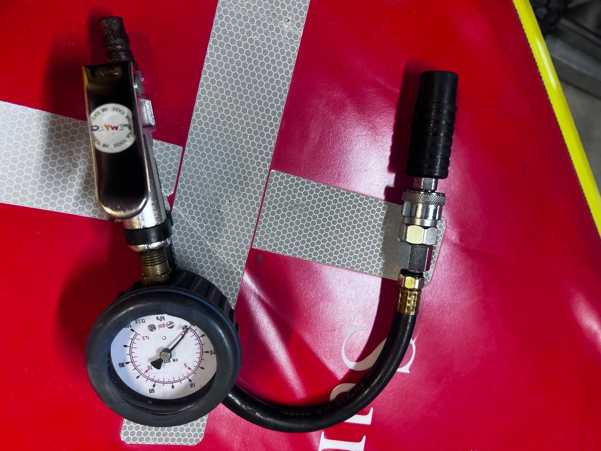Air hose gauge with two valves on a red and silver surface