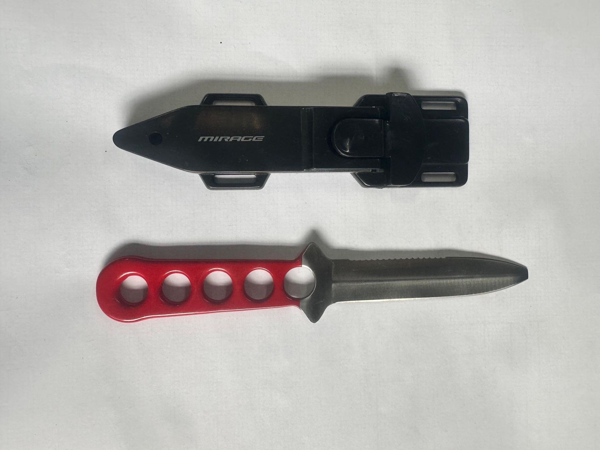 Black flashlight and red-handled knife on a light background