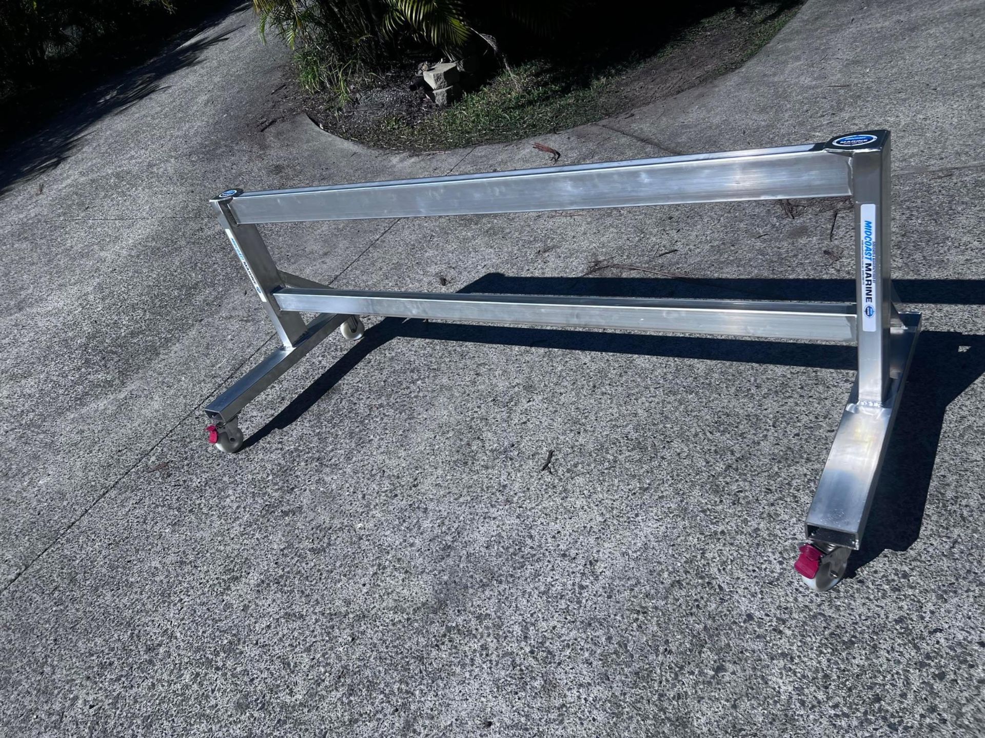 Metal cart frame with black wheels on a concrete surface outdoors