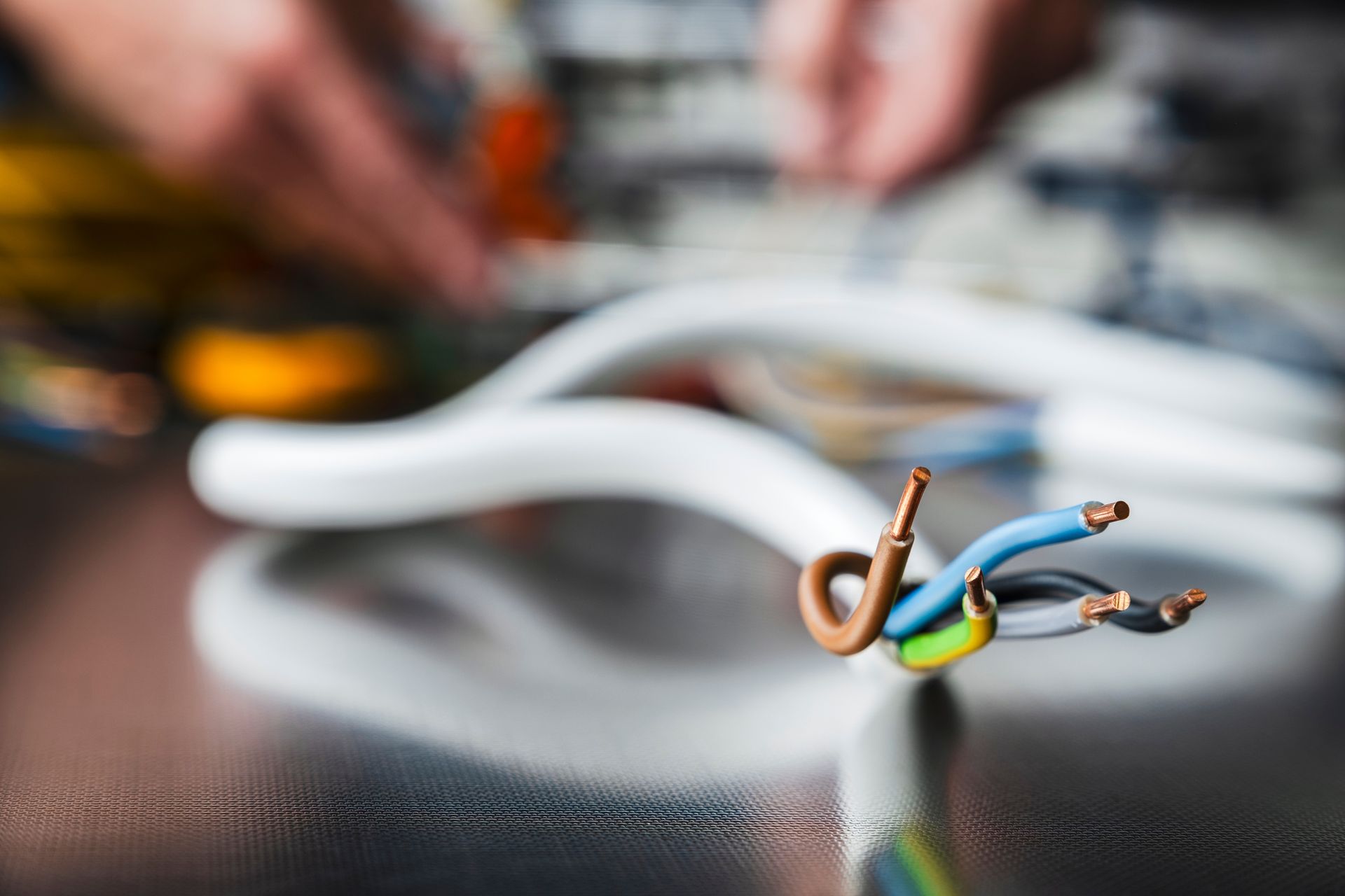 Close-Up of Exposed Electrical Wires with A Person Working in The Blurry Background — Townsville Electrical and Appliance Repairs In Douglas, QLD