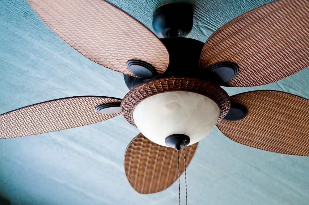 Ceiling Fan With Wicker-style Blades And A Light Fixture, Against A Blue Ceiling — Townsville Electrical and Appliance Repairs In North Ward, QLD