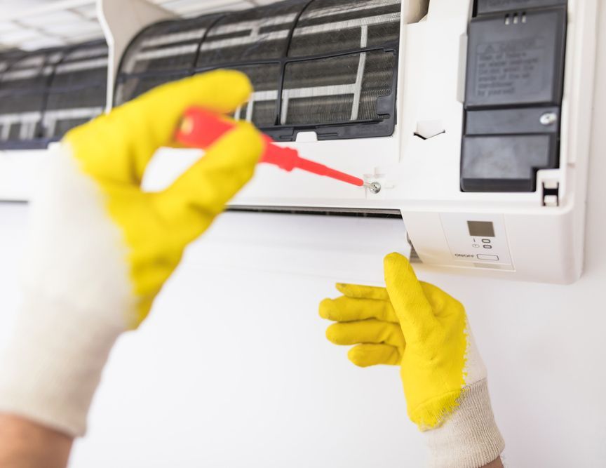 Man Wearing Yellow Gloves Repairing Air Conditioning — Townsville Electrical and Appliance Repairs In Aitkenvale, QLD