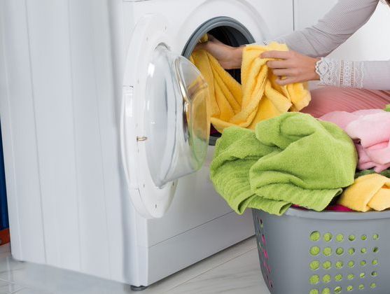 Woman Putting Clothes In The Washing Machine Appliances — Townsville Electrical and Appliance Repairs In Aitkenvale, QLD