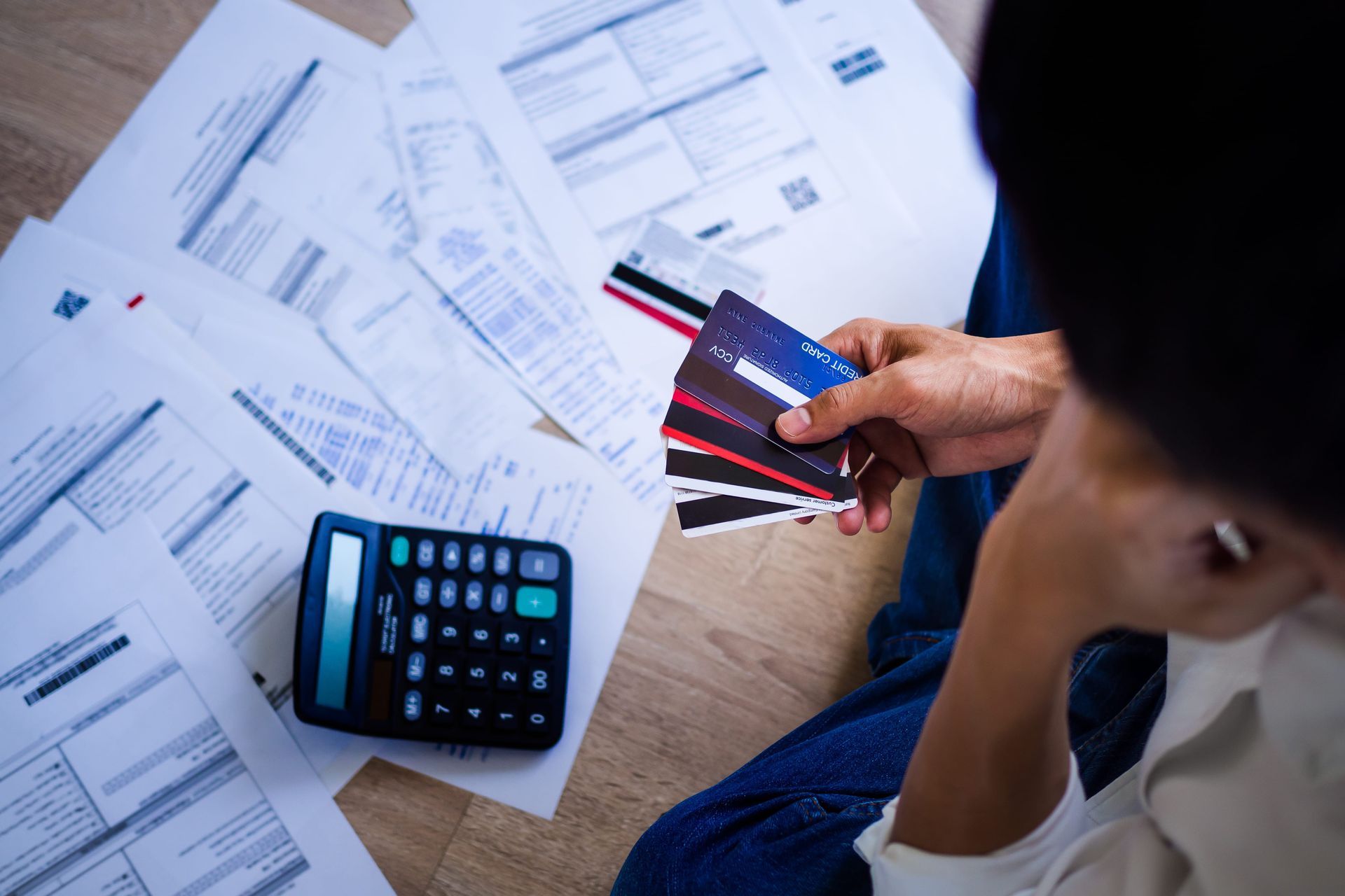 Person reviewing bills beside a calculator and credit cards on a desk