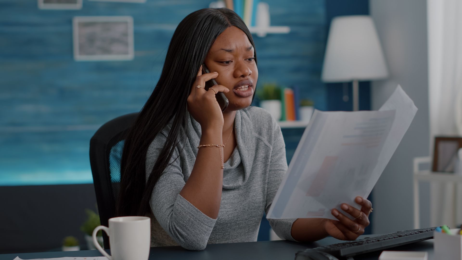 Woman on phone, holding papers, looking concerned in an office setting, light skin tone, neutral colors.
