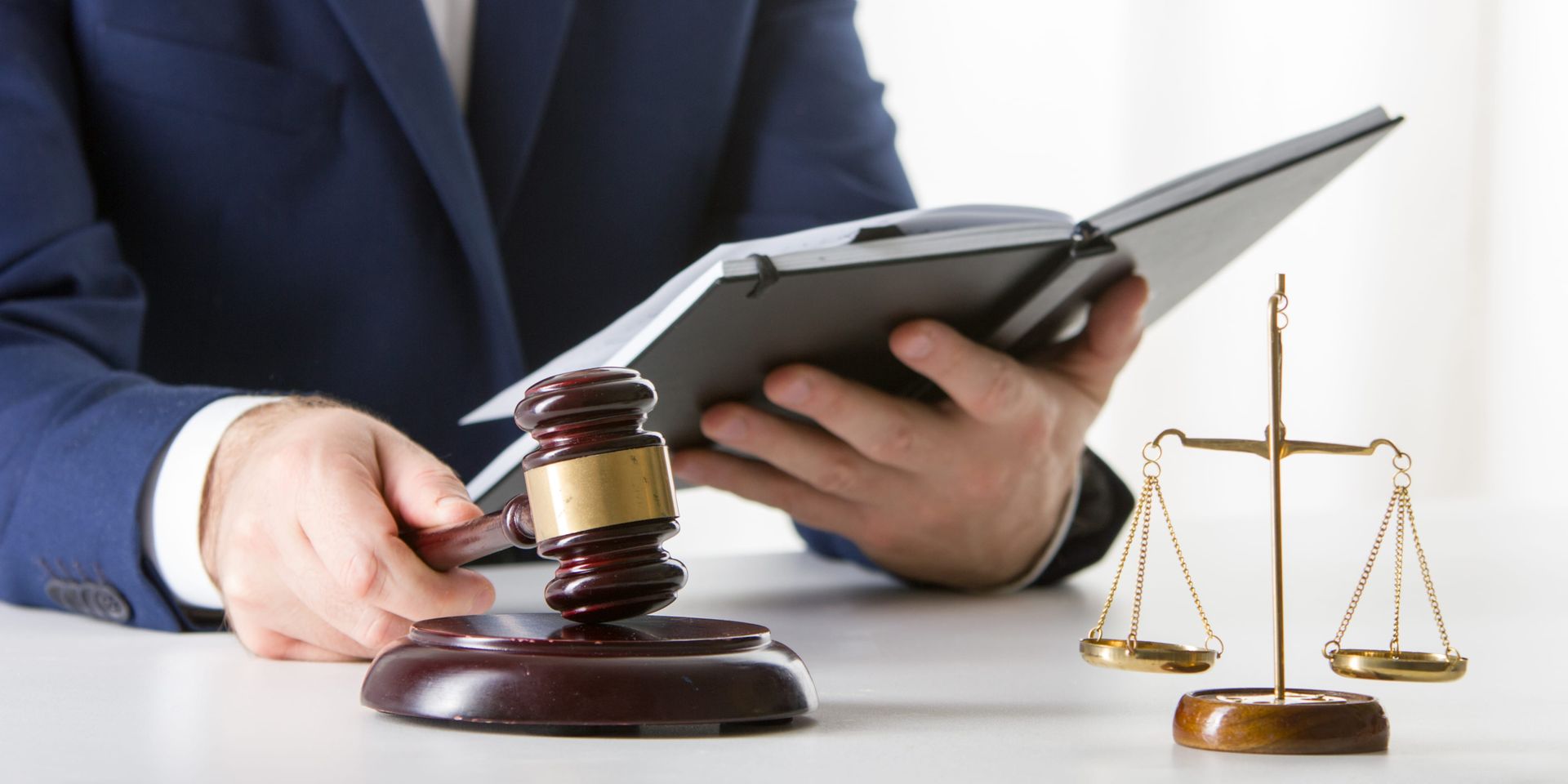 Lawyer with gavel and scales reviewing documents on a tablet at a desk