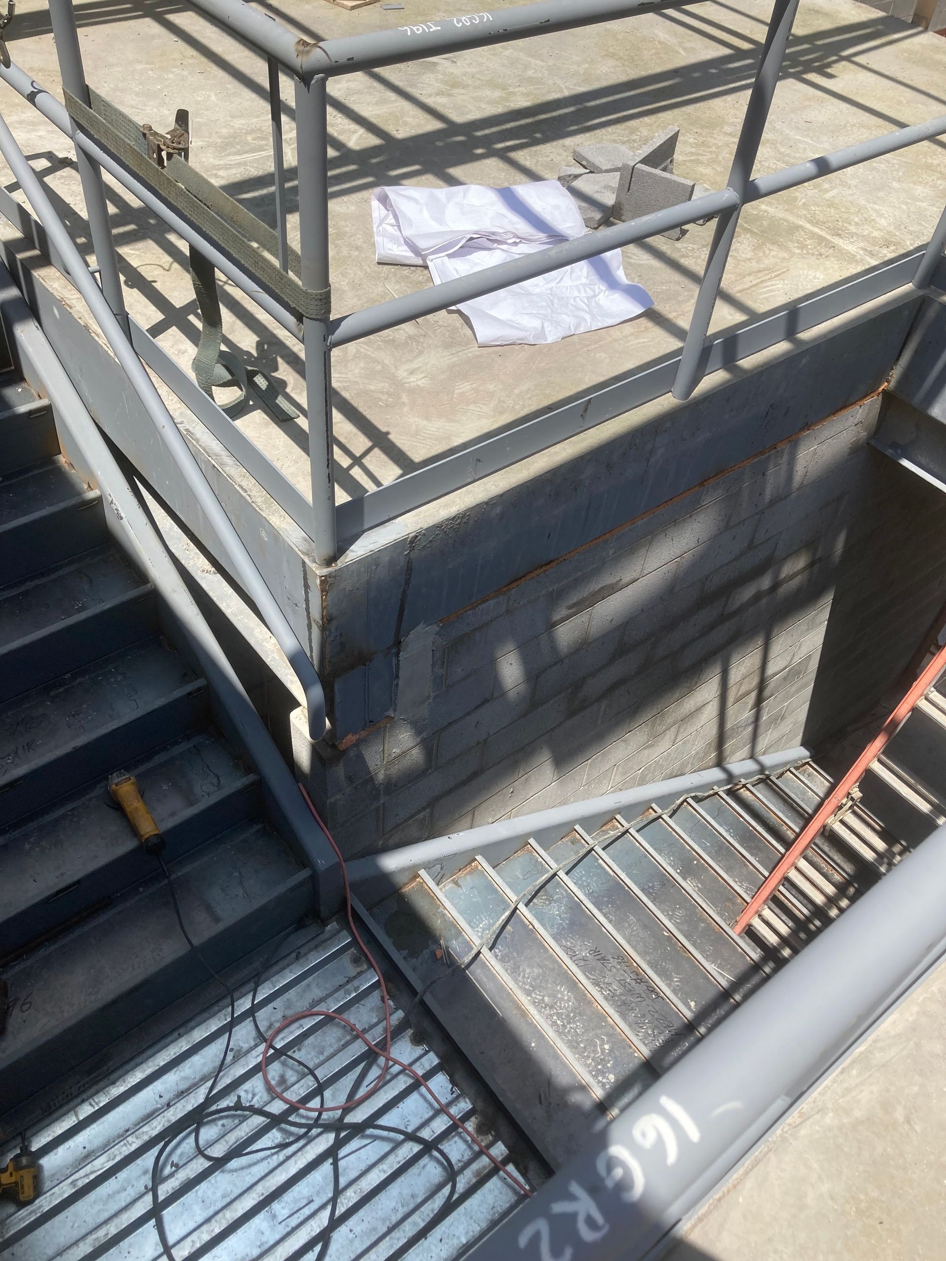 Metal staircase with railing and grated floor section, possibly under construction.