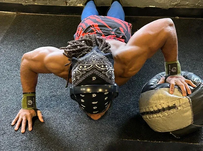 Person doing a push-up with one hand on a medicine ball in a gym.