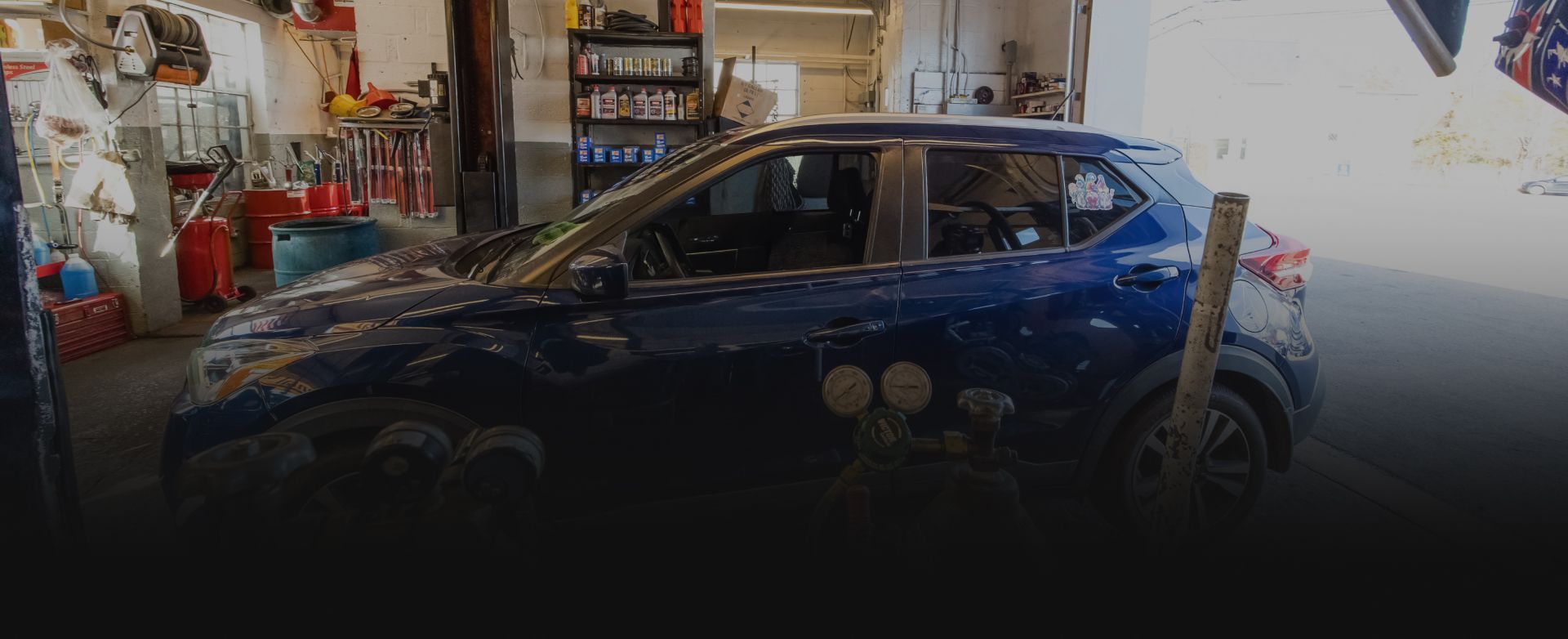 Blue sports car parked in a cluttered garage, side view. | Expert Auto Service & Licensing