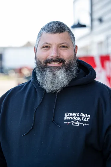 Smiling bearded man in a navy hoodie | Expert Auto Service & Licensing