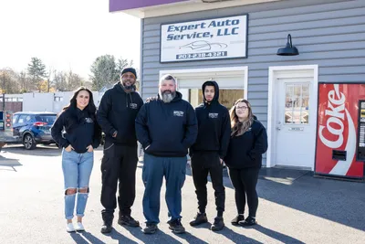 Five people standing outside Expert Auto Service, LLC in winter, with a Coke vending machine by the door | Expert Auto Service & Licensing