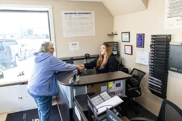 Customer and clerk talking across a reception desk in a small office lobby | Expert Auto Service & Licensing