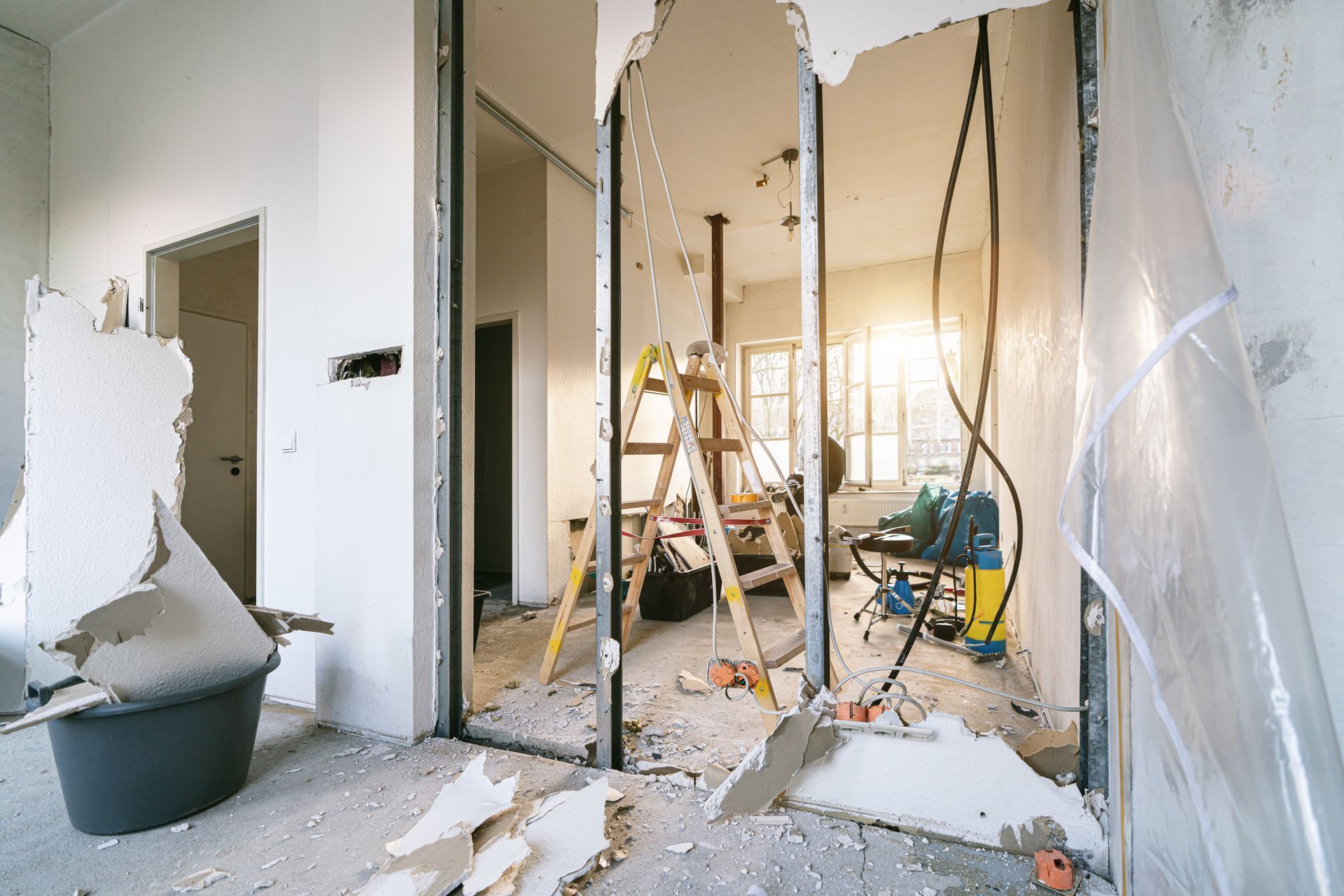 Partially demolished room with exposed walls, ladder, debris, and renovation tools