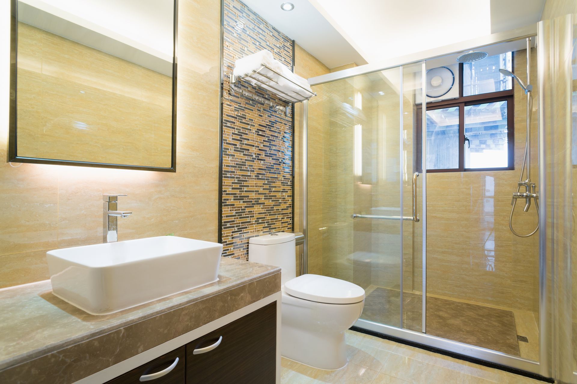Modern bathroom with glass shower, white toilet, and vessel sink on a stone vanity.