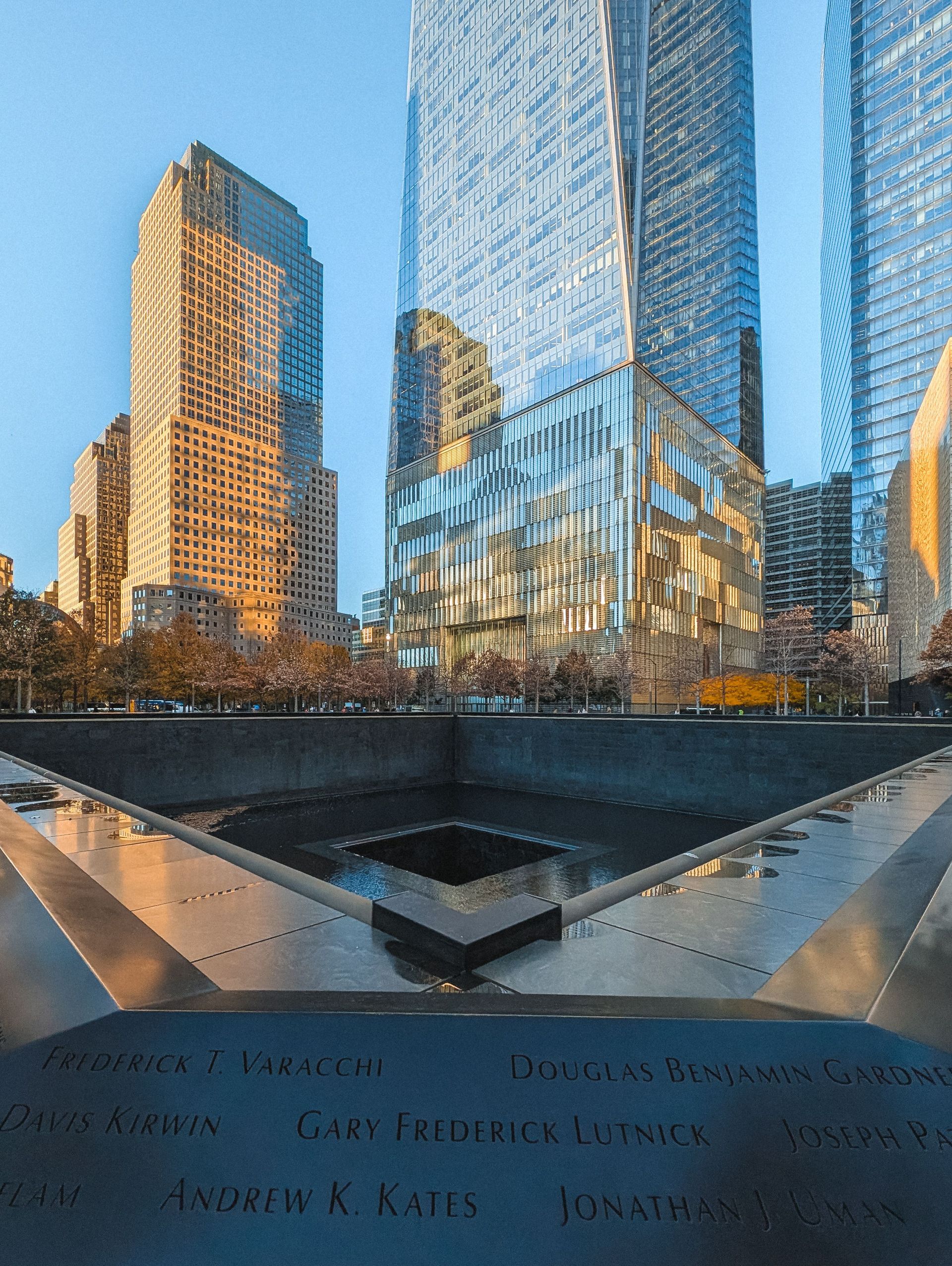 9/11 Memorial reflecting pool with Manhattan skyscrapers and blue sky
