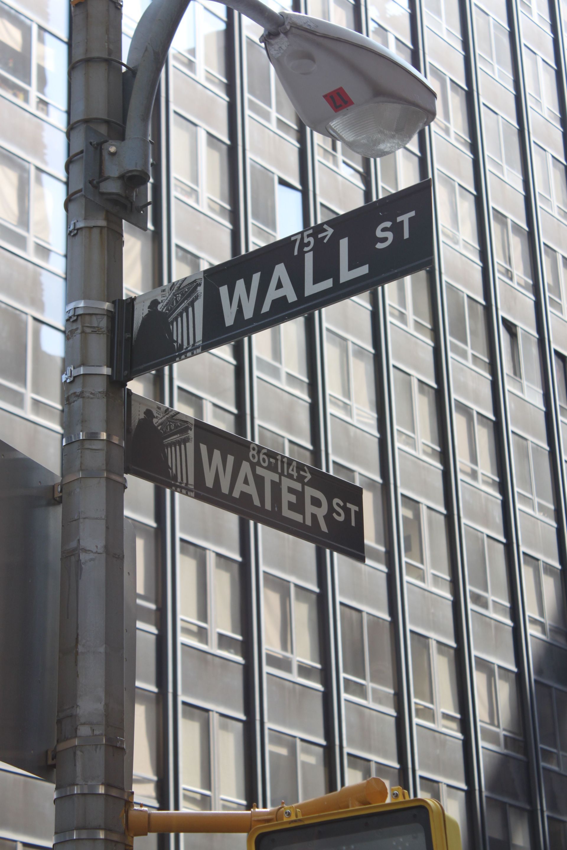 Street signs for Wall St and Water St on a city building corner.