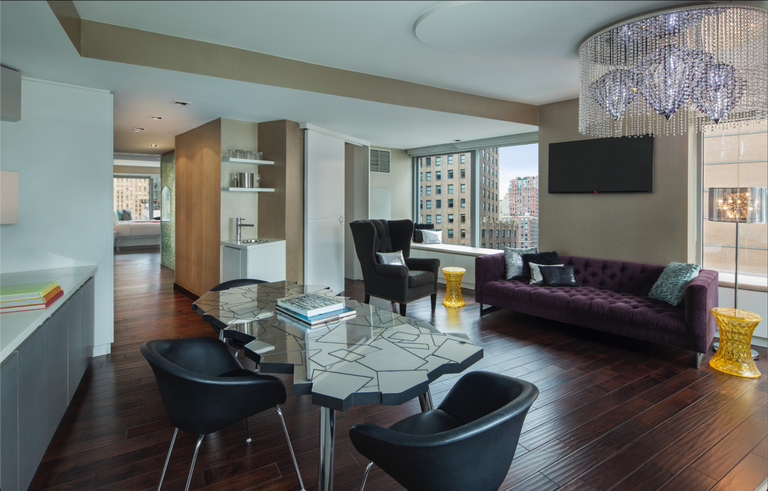 Modern luxury living room with dark wood floors, purple sofa, glass coffee table, and city view windows
