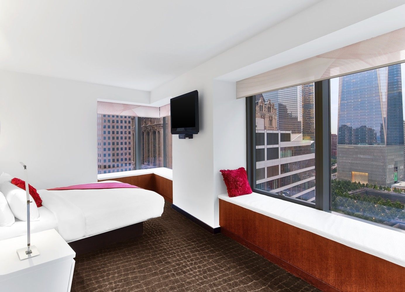 Bright hotel room with two beds, large windows, and a city view