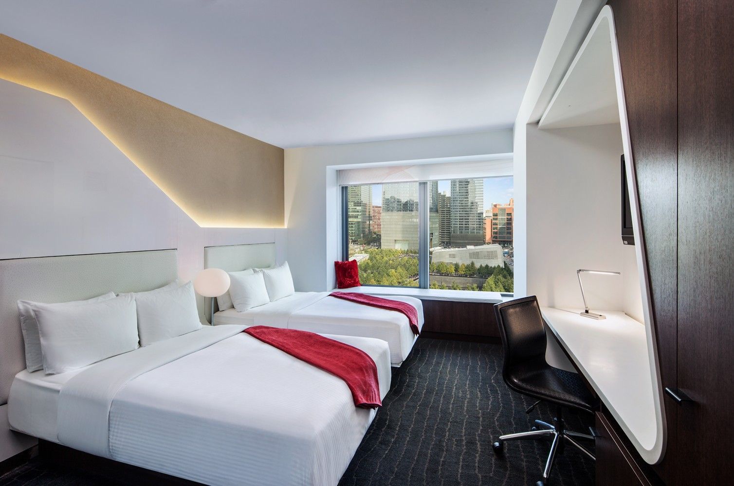 Modern hotel room with two twin beds, large window, and city view