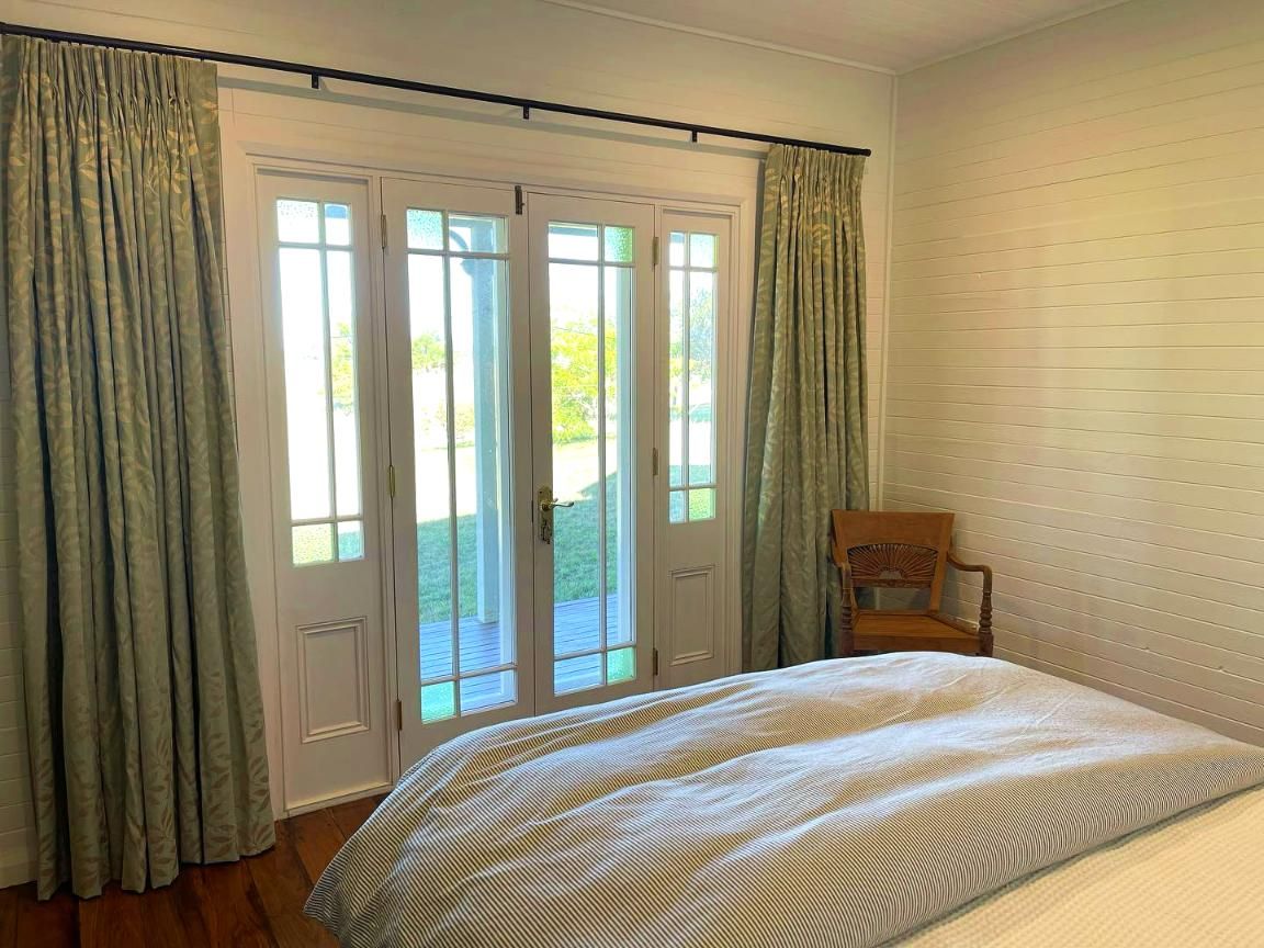 Bedroom With Bed, French Doors, Green Curtains, And Wooden Chair — JSF Interiors Goulburn in Gerringong, NSW