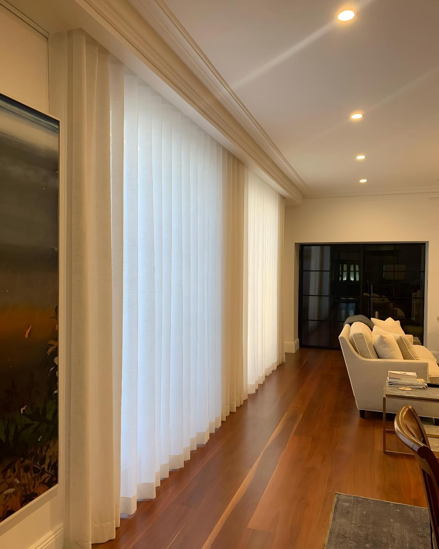 Long, sheer white curtains cover a large window in a room with hardwood floors and recessed lighting — JSF Interiors Goulburn in Goulburn, NSW