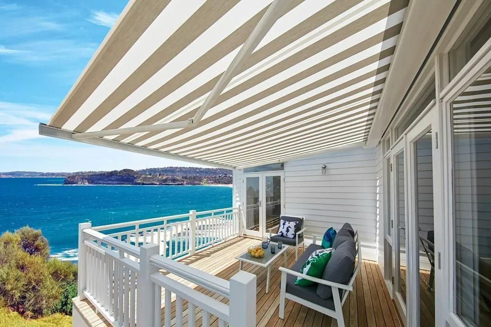 Balcony Overlooking Ocean With Striped Awning And White Furniture — JSF Interiors Goulburn in Goulburn, NSW