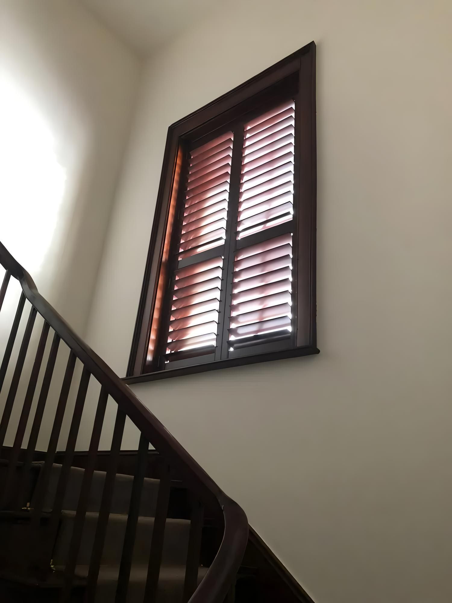 Wooden staircase leading to a window with brown shutters on a beige wall — JSF Interiors Goulburn in Goulburn, NSW