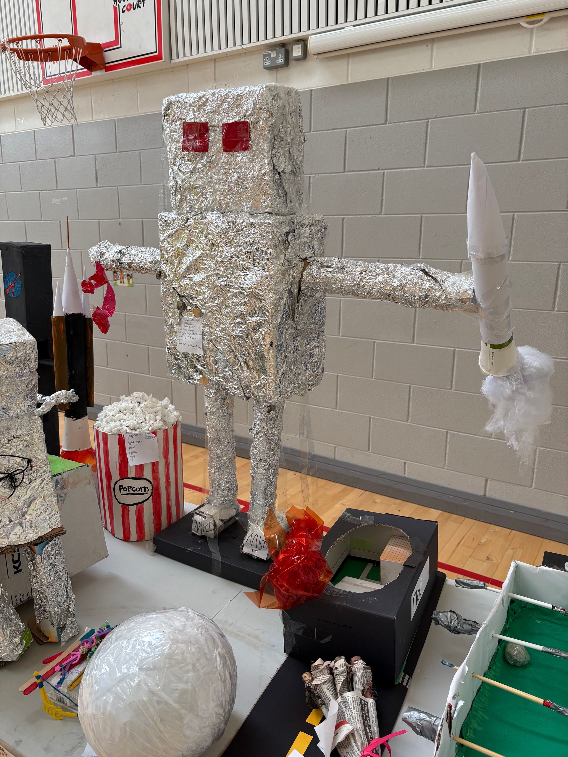 Foil robot and white bunny decorations beside a green staircase in a school hallway