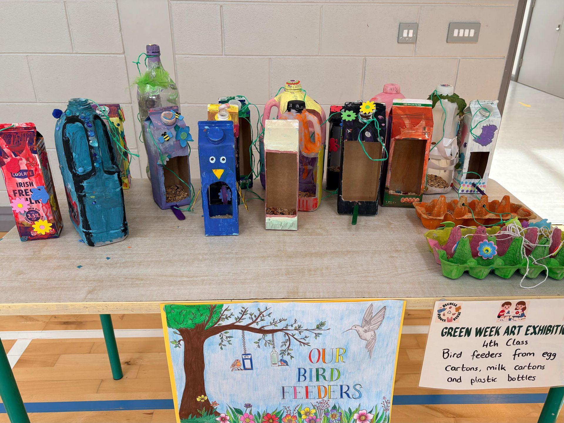 Colorful handmade bird houses arranged on a table in a classroom, with a bird-themed sign in front.