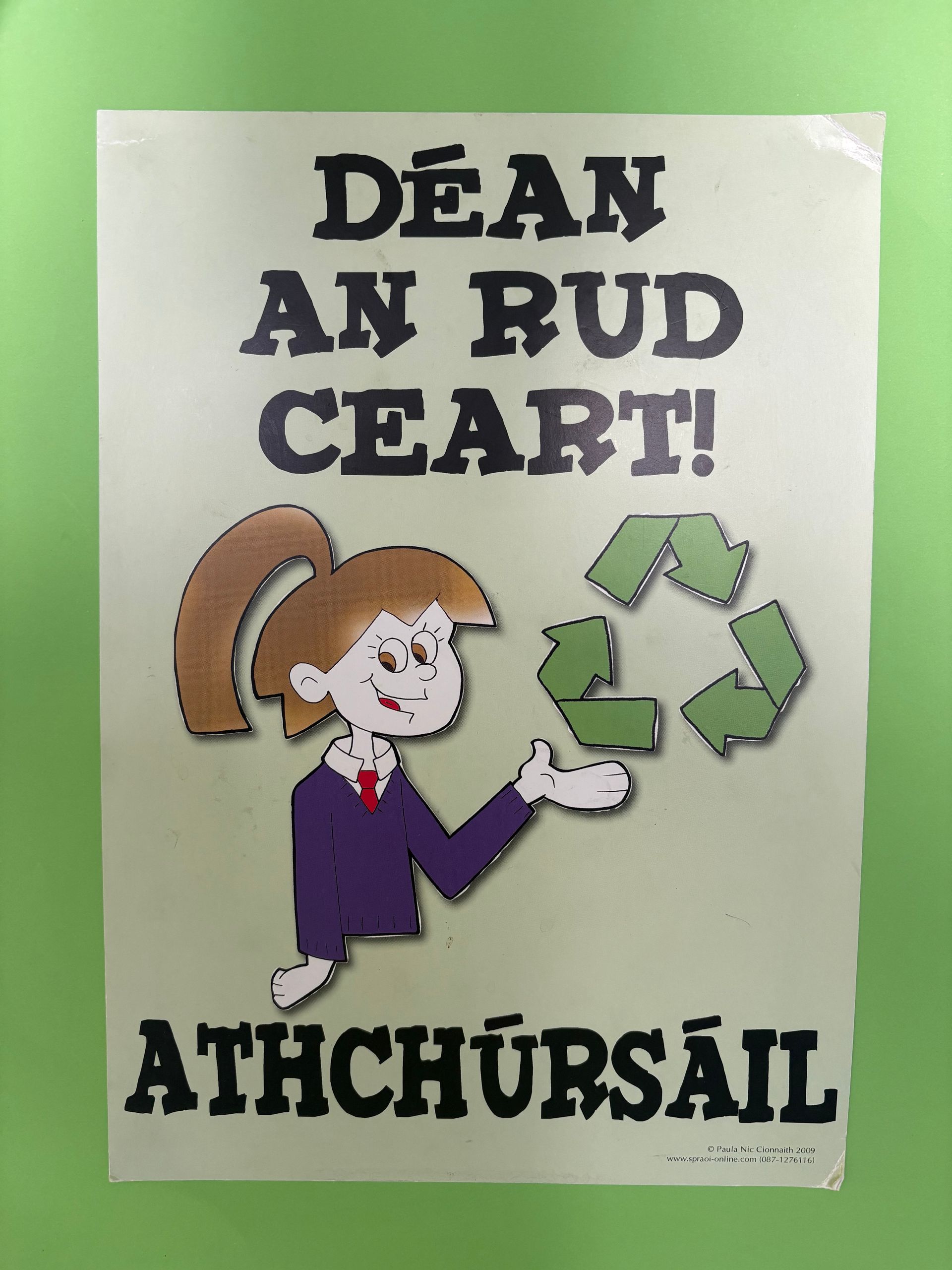Irish recycling poster with a cartoon child and recycle symbol, text reading “DEAN AN RUD CEART! ATHCHÚRSAÍL”