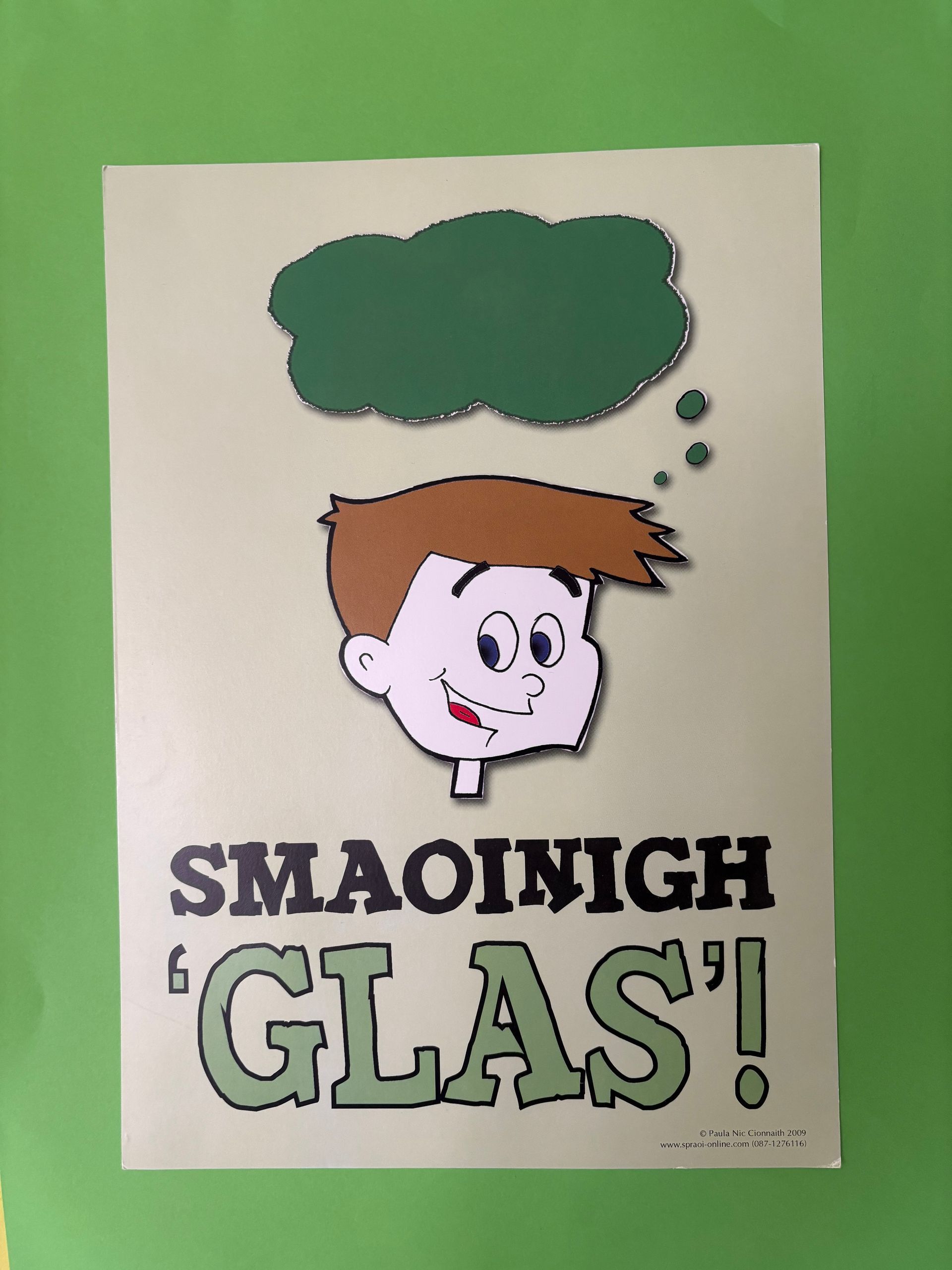 Cartoon head with thought bubble and the text “SMAOINIGH ‘GLAS!’” on a green background.
