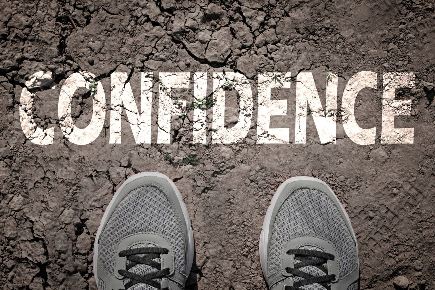 A pair of shoes with the word confidence written on the ground.