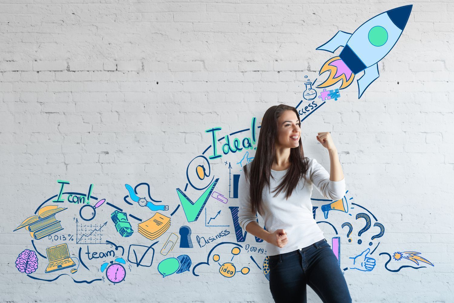A woman is standing in front of a brick wall with a drawing of a rocket coming out of it.