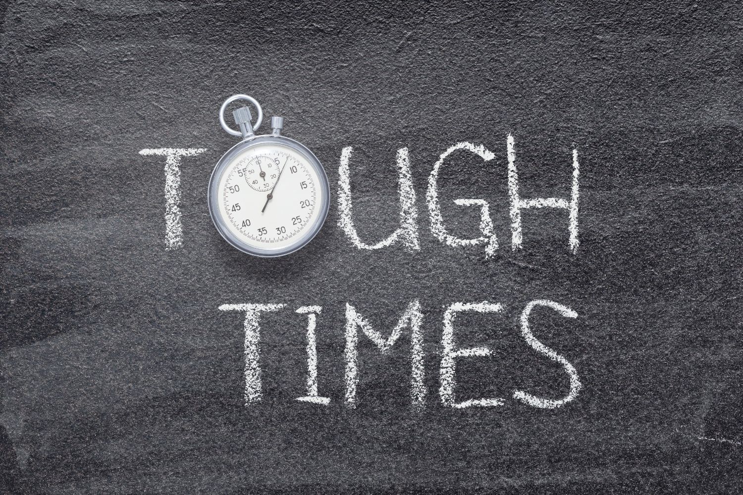 A blackboard with the words `` tough times '' and a stopwatch on it.