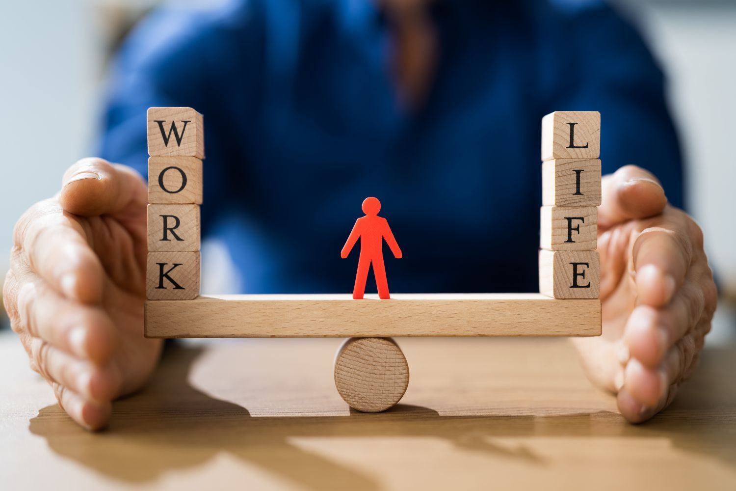 A person is holding a wooden balance between work and life.