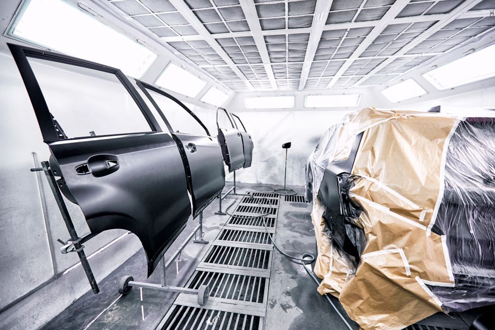 Car Being Painted in a Spray Booth; Detached Door on Stand — Mid Coast Smash Repairs In Mid North Coast, NSW