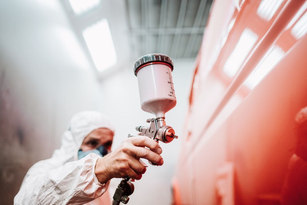 Person in Protective Suit Using a Paint Sprayer — Mid Coast Smash Repairs In Tuncurry, NSW