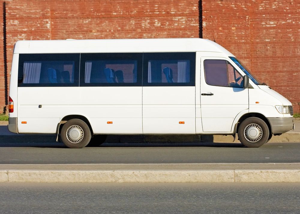 White Passenger Van Parked in Front of a Brick Wall, on a Paved Road — Mid Coast Smash Repairs In Tuncurry, NSW