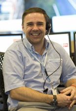 man with headset on A man wearing a headset is smiling while sitting in front of a computer.