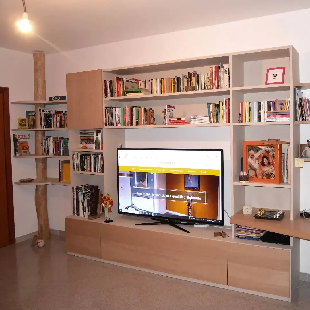 Libreria in legno integrata con TV e libri in un soggiorno molto luminoso.