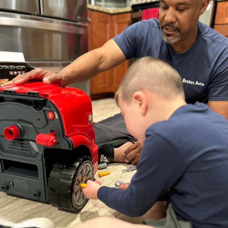 A man and a boy are playing with a toy truck
