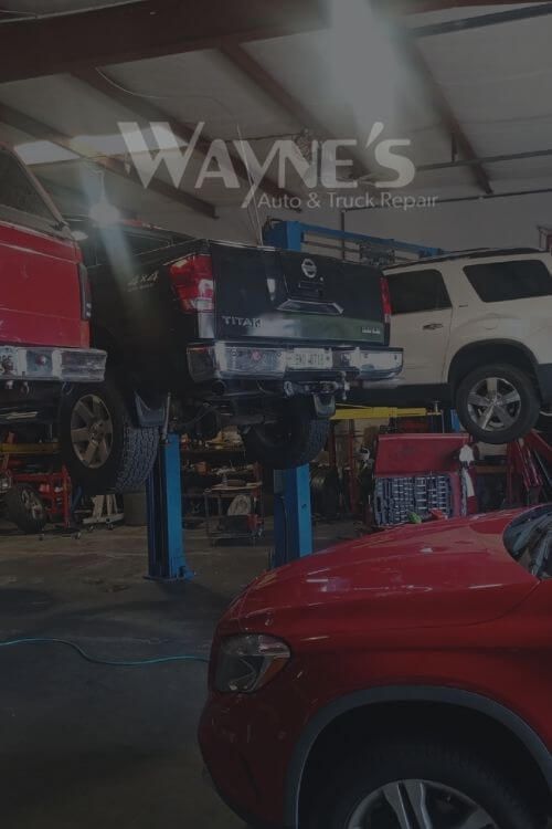 Inside a garage, vehicles on lifts; Wayne's Auto & Repair logo is visible.