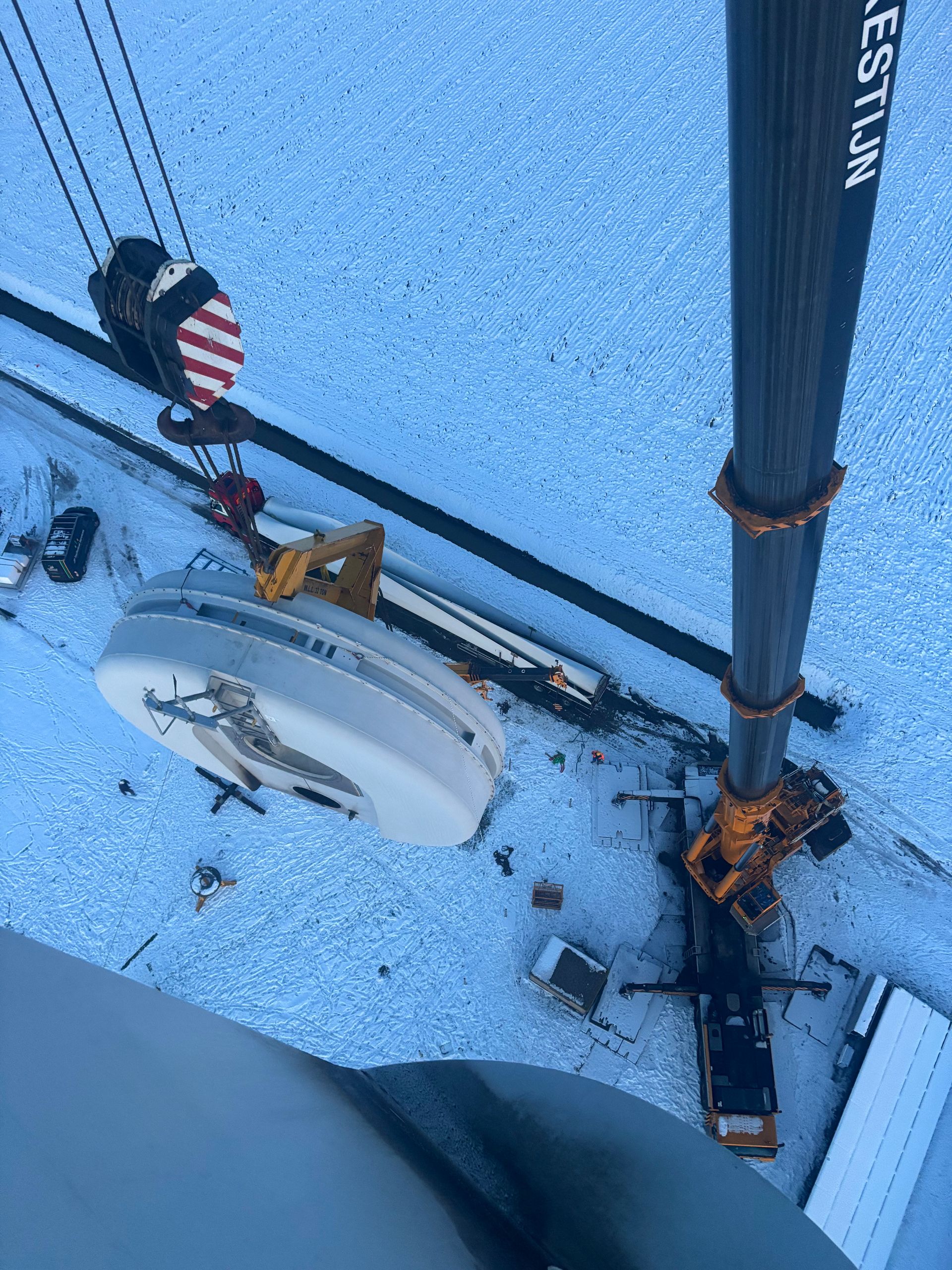 Snowy rooftop with utility equipment, pipes, and a striped valve handle beside a vertical pole
