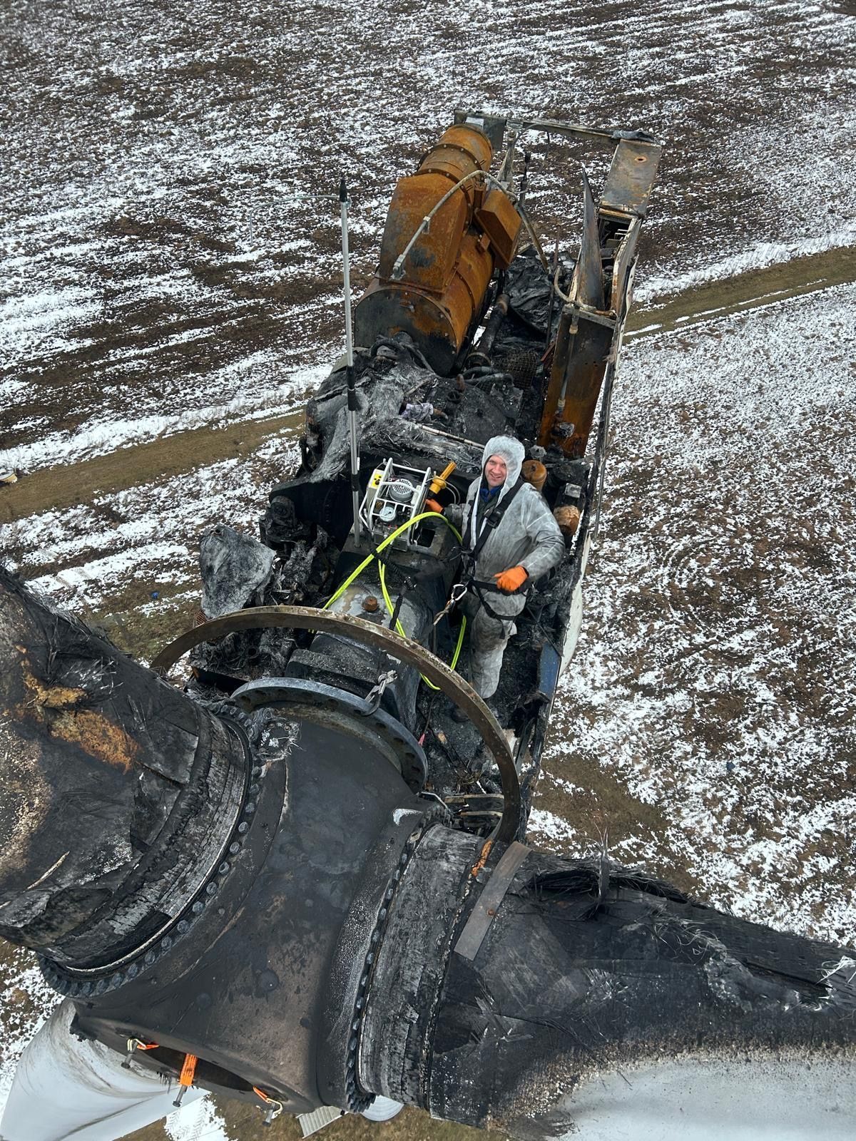 Worker standing beside large black industrial machine in snowy field
