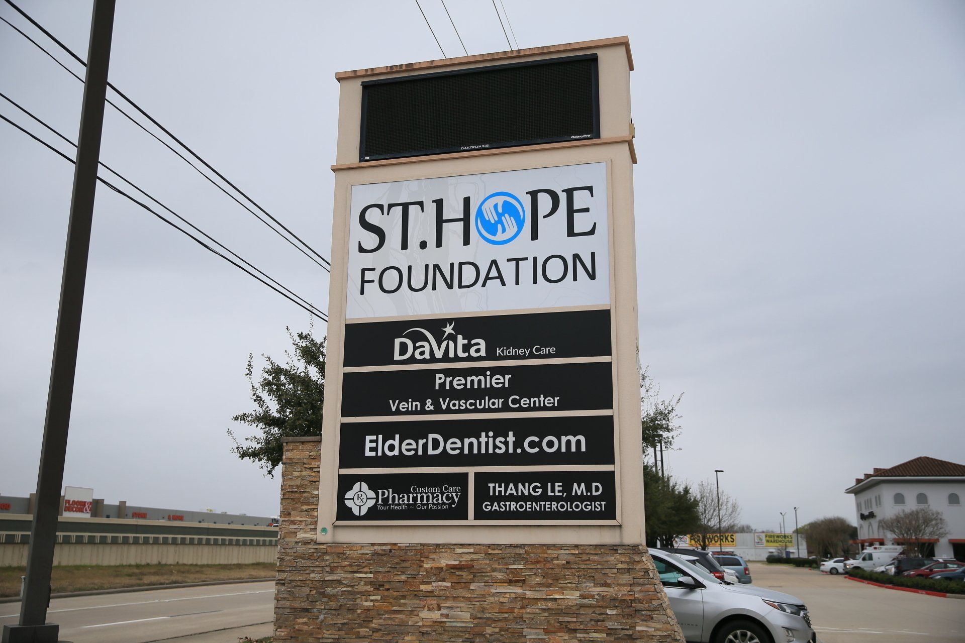 A sign for St. Hope Foundation and other medical offices in a parking lot on an overcast day.