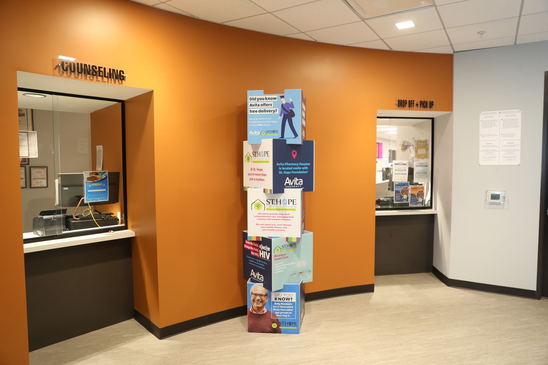 An office hallway with orange walls, featuring two service windows labeled 