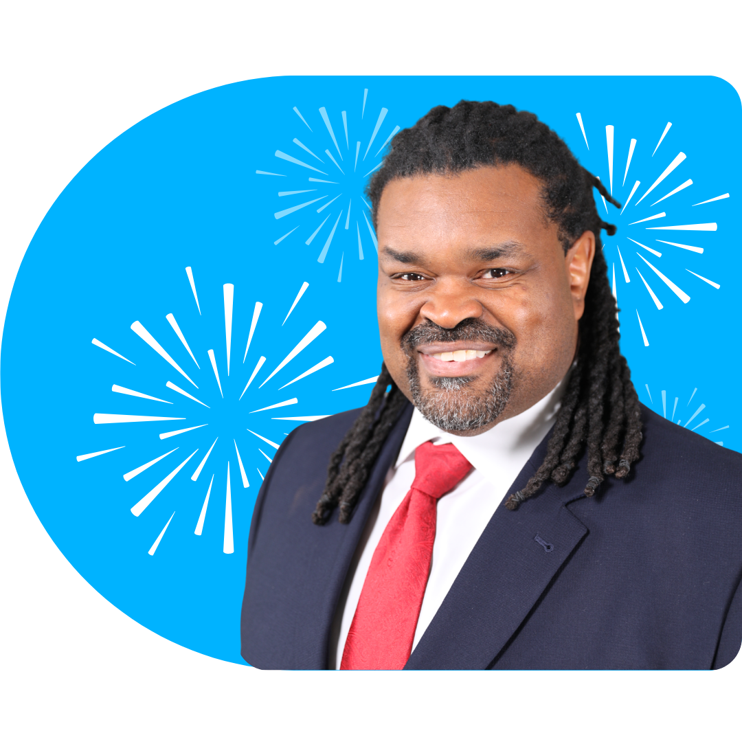 A person with blonde highlights, wearing a black blazer and necklace, posing against a blue background with white fireworks.