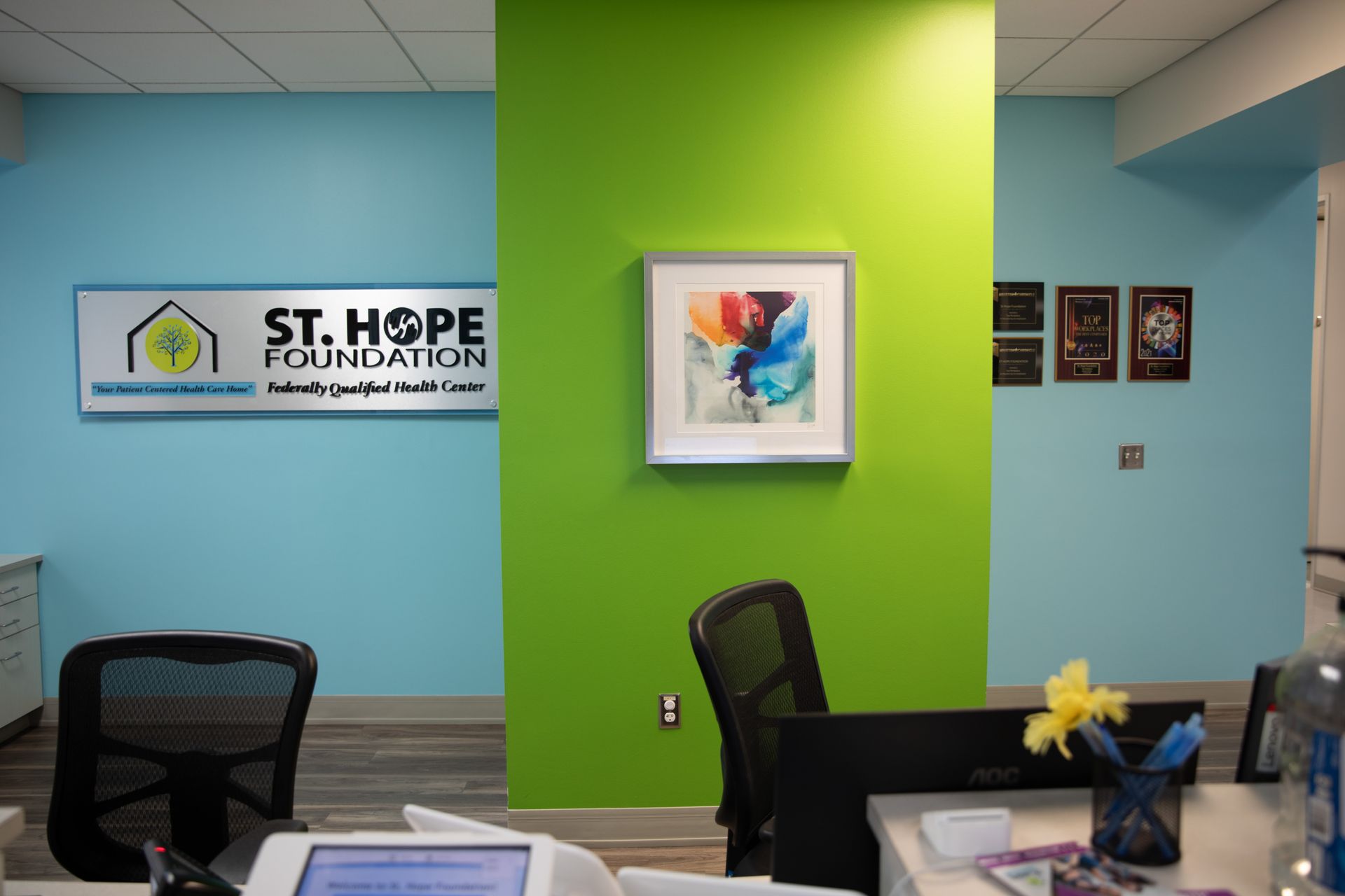 Interior view of the St. Hope Foundation reception area featuring bright green and blue walls and a framed abstract painting.