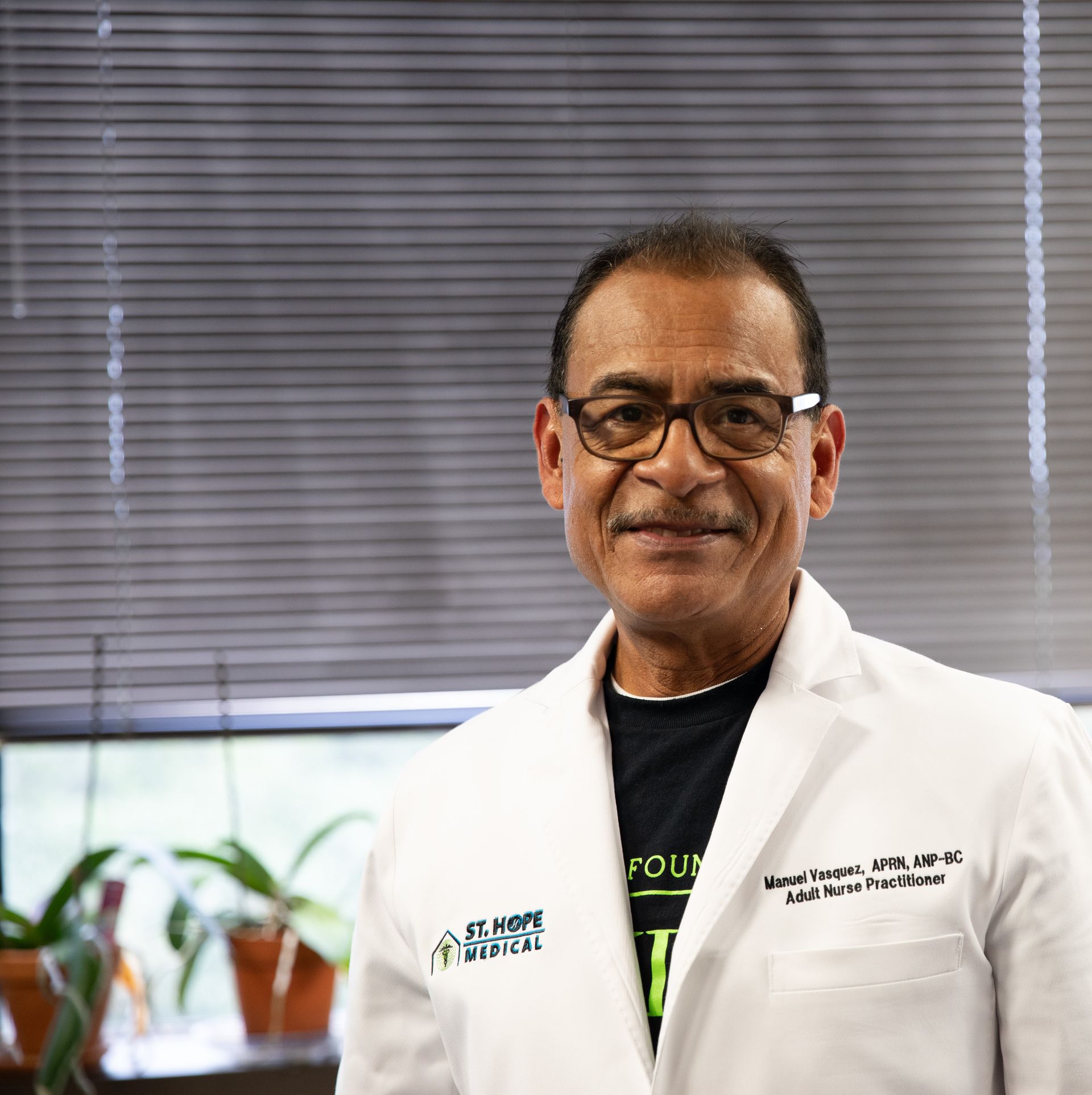 A professional healthcare provider in a white coat with St. Hope Medical branding, smiling in an office setting.